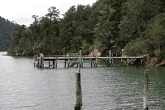 Ponton en bois le long d'une côte boisée et pentue.