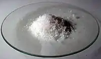 Poudre grossière blanche dans un verre de montre.