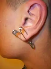 Oreilles avec épingle de sûreté en piercing.