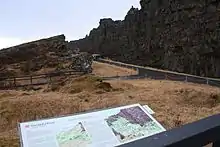 Ruine avec un panneau explicatif près d'une faille.