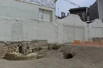 Base d'une tour de l'enceinte de Philippe Auguste, mise au jour lors des fouilles archéologiques dans l'Institut de France en 2015, avant la réalisation d'un nouveau bâtiment. L'enceinte marque la frontière entre l'Institut de France et la Monnaie de Paris. On voit également l'entrée d'un égout construit par Louis Le Vau dans les anciens fossés de l'enceinte, lors de la construction du Collège des Quatre-Nations au XVIIe&nbsp;siècle.