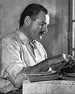 Ernest Hemingway assis devant une machine à écrire.