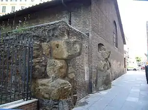 Photographie en couleurs de gros blocs de pierre encastrés dans le pignon d'une maison.