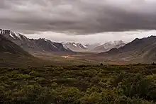 Une grande vallée où la pluie s'est invitée, les sommets déjà tapissés de neige, le bas d'un vert bientôt éteint.