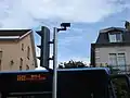 Un bus passant devant un feu tricolore. On retrouve en haut le boîtier et en bas le feu « losange ».