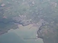 Photo à très haute altitude montrant deux agglomérations sur le pourtour d'une baie. La mer est au bas de l'image.