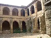 Photographie couleur d'un cloître monastique à deux niveaux.