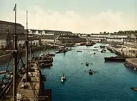 Le port et l’arsenal en Penfeld vus depuis le Grand Pont en 1895 : de gauche à droite, côté Recouvrance, la caserne du 2e&nbsp;dépôt des équipages de la flotte (dit la Cayenne), les ateliers du plateau des Capucins ; côté Brest même, en arrière-plan la corderie et le bagne la surplombant, et à droite, la majorité générale.