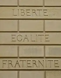 Devise française « liberté, égalité, fraternité » gravée sur un mur.