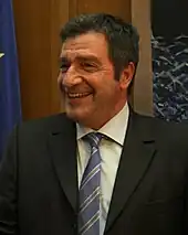 Photographie d'un homme souriant avec en arrière-plan le drapeau européen.