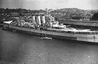 HMS&nbsp;Sussex accostant à Singapour, 12 septembre 1945.