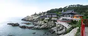 Photographie d'un temple surplombant la mer sur des rochers.