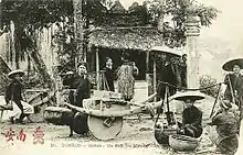 Photographie montrant des hommes et des femmes asiatiques portant des paniers.