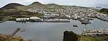 Heimaey vu vers le sud depuis Heimaklettur avec les volcans Eldfell et Helgafell à gauche et le port au premier plan.