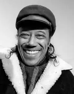  un homme souriant, casquette de marin, manteau.