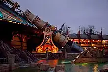 Canon cuivré reposant sur un bâtiment doré et bleu.