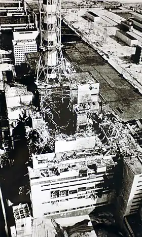 Photo aérienne du bâtiment du réacteur no&nbsp;4 prise quelques mois après l’accident. Le réacteur no&nbsp;3 est visible derrière la cheminée de ventilation.