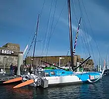 Vu de trois quarts arrière, voilier blanc et bleu amarré au ponton.