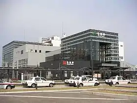 Photo couleur d'une entrée de gare avec une station de taxi à l'avant-plan