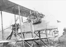 Photographie noir et blanc de deux hommes assis dans un biplan.