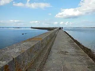 Photographie en point de fuite d'une jetée s’avançant dans la mer.