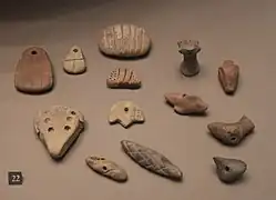Jetons en argile aux formes diverses, incisés de motifs linéaires et de signes ronds.