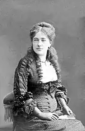 Portrait photographique d'une femme assise sur une chaise et portant une robe.