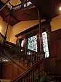 Le sous-sol et le deuxième étage sont reliés par un grand escalier bordé de fenêtres en verre colorées.