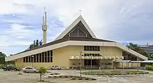 Photographie d'une cathédrale catholique de style moderne et de son parking.
