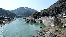 Photo couleur d'un couleur d'eau à l'eau bleu-vert avec un paysage de montagne en arrière-plan.
