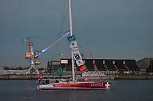 De profil, voilier blanc et rouge, voiles amenées, immobile au milieu d'un bassin.