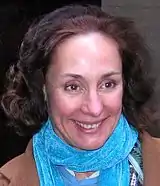Photo d'une femme souriante avec un foulard bleu autour de son cou.