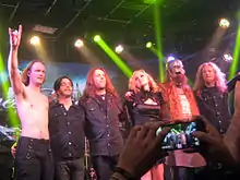 Six membres d'un groupe saluent son public en se faisant prendre en photo après un de leurs concerts