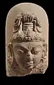 Linga à visage divin : le troisième œil sur le front symbolise l'omniscience de Shiva. VIIIe – IXe&nbsp;siècle. Calcaire, H. 25&nbsp;cm. Inde du Nord