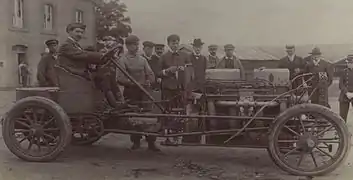 Photo d'un homme prenant la pause au volant d'une voiture sans capot moteur.