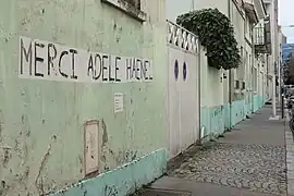 Collage sur un mur marqué « Merci Adèle Haenel » et des coordonnées sur les réseaux sociaux