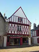 Vue d'une façade de maison blanche aux pans de bois rouges.