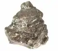 Melonite et calavérite, Kambalda, Coolgardie Shire, Australie occidentale. La mélonite est un tellurure de nickel rare. Il s'agit d'une masse foliée solide et voyante de mélonite lustrée légèrement irisée avec un peu de pyrite dorée et cuivrée d'un côté de cette importante région productrice de nickel.