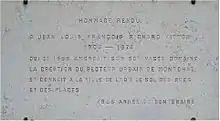 Plaque commémorant grise avec texte gravé en lettres capitales.