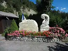 Le monument est formé d’une pierre tranchée, où sont inscrits les noms, et d’une femme stylisée, affligée, à genoux, la tête dans la main.