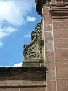 Volute en pierre blanche sur un portail en grès rose du XVIIIe&nbsp;siècle (abbaye de Moyenmoutier, Vosges.