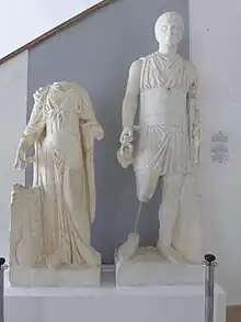 Vue d'un groupe de deux statues dont l'une, une femme, n'a pas de tête et l'autre, un homme, porte une cruche et une sorte de bâton.