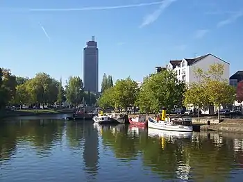 L'Erdre au premier plan, des bateaux sont à quai, les rives sont plantées d'arbres.