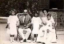 Photographie en noir et blanc d'un couple assis sur une terrasse et entourée de trois petites filles.