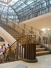 Photographie d'un grand escalier et du toit en verre.