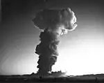La boule de feu de l'essai thermonucléaire Hood vu du centre de contrôle à 14 km de distance au niveau du sol. L'onde de choc a provoqué le tremblement de fenêtres à 300 miles de distance en Californie, alors que l'éclair lumineux a été aperçu par un pilote d'avion qui volait au-dessus des îles Hawaï, à environ 2&nbsp;700&nbsp;miles du Nevada Test Site.