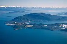 Une île vue des airs. Entourée d'une masse d'eau, on distingue la côte.