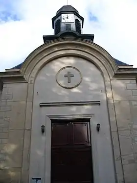 Photo d'un bâtiment surmonté d'un clocher, avec une grande porte rouge