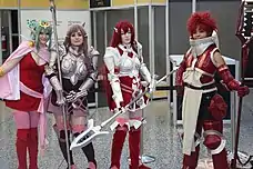 Quatre jeunes femmes déguisées en armure médiévales dans les tons roses et rouges.