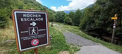 Photographie en couleur d'un panneau indiquant le sentier pour se rendre au rocher d'escalade.